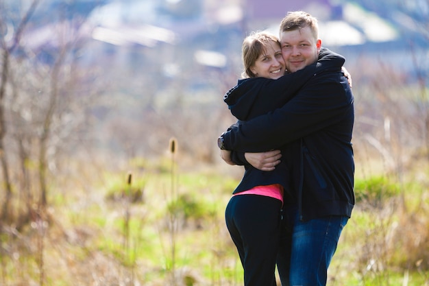 Radosna śliczna Uśmiechnięta Para Obejmuje. Młody Mężczyzna W Swetrze Przytula Blondynkę W Ciepły Wiosenny Dzień. Romantyczne Udane Relacje I Koncepcja Szczęśliwych Chwil.