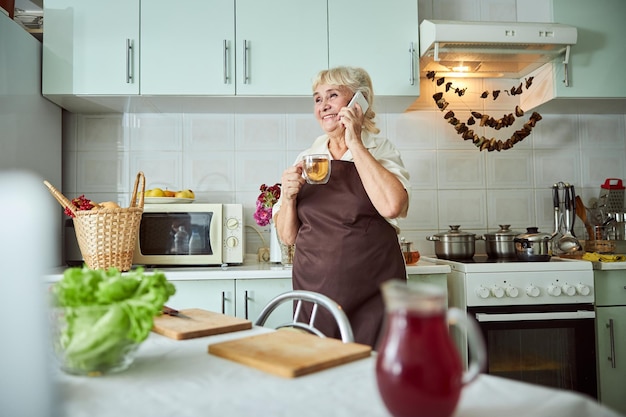 Radosna Starsza Kobieta Rozmawia Przez Telefon W Kuchni