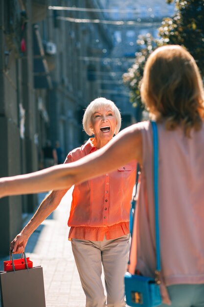 Radosna starsza kobieta uśmiechająca się, gdy spotyka córkę na ulicy po zakupach