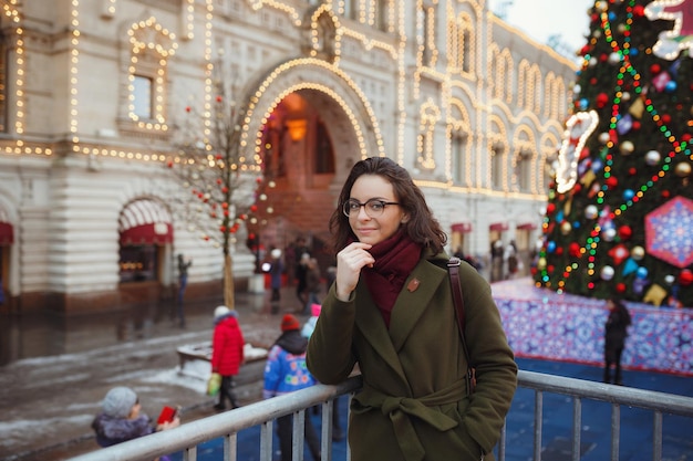 Radosna szczęśliwa dziewczyna ciesząc się śnieżną pogodą na ulicy Modna młoda kobieta z długimi włosami brunetki chodzenie w śniegu zabawy uśmiechający się świąteczny nastrój nowy rok nadchodzi prawdziwe szczęście