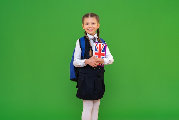 Radosna uczennica z angielskim podręcznikiem dziewczyna w szkolnym mundurku zdobywająca wiedzę nauka języków obcych na białym tle
