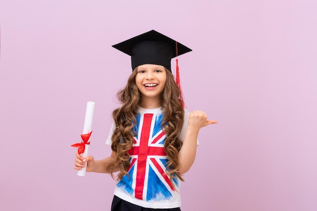 Radosna uczennica z dyplomem i uroczystym kapeluszem absolwenta Studentka w koszulce z angielską flagą ucząca się języków obcych uczennica wskazuje palcem na reklamę