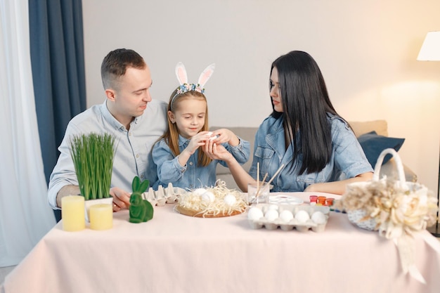 Radosne rodzinne spotkanie przy stole w nowoczesnej, lekkiej kuchni i wspólne malowanie pisanek