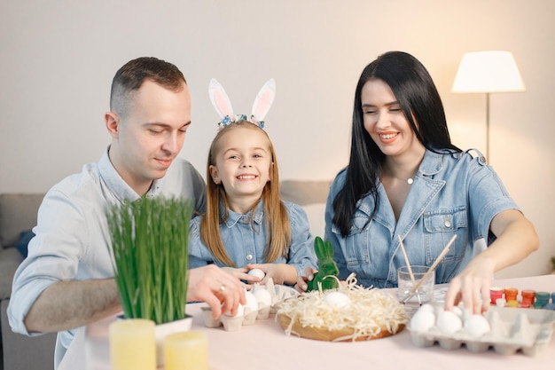 Radosne rodzinne spotkanie przy stole w nowoczesnej, lekkiej kuchni i wspólne malowanie pisanek