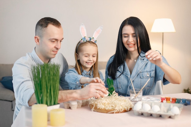 Radosne rodzinne spotkanie przy stole w nowoczesnej, lekkiej kuchni i wspólne malowanie pisanek