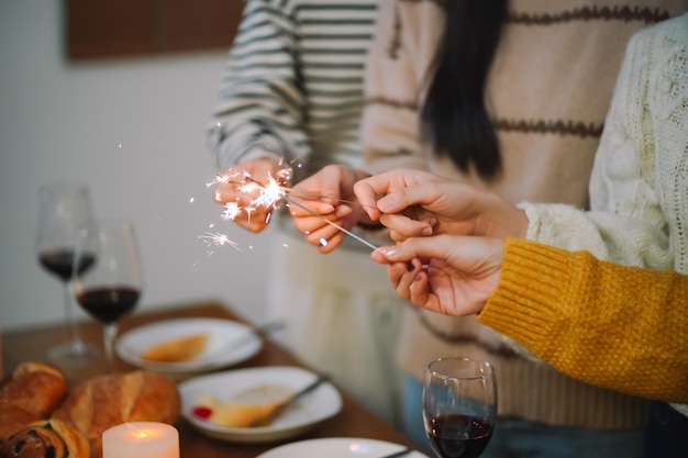 Radośni przyjaciele cieszący się domem Urodzinowe przyjęcie świąteczne Azjatyccy przyjaciele trzymają światła z błyszczącym Sparklerem świętującym przyjęcie świąteczne lub sylwestrowe