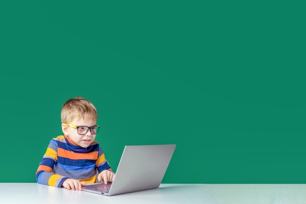 Radosny chłopiec w okularach bawi się w laptopie Skopiuj miejsce