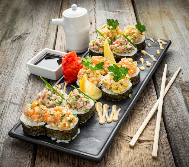 Zdjęcie rainbow sushi roll z łososiem, węgorzem, tuńczykiem, awokado, krewetką królewską, serek philadelphia, kawior tobica, chuka. menu sushi. japońskie jedzenie.