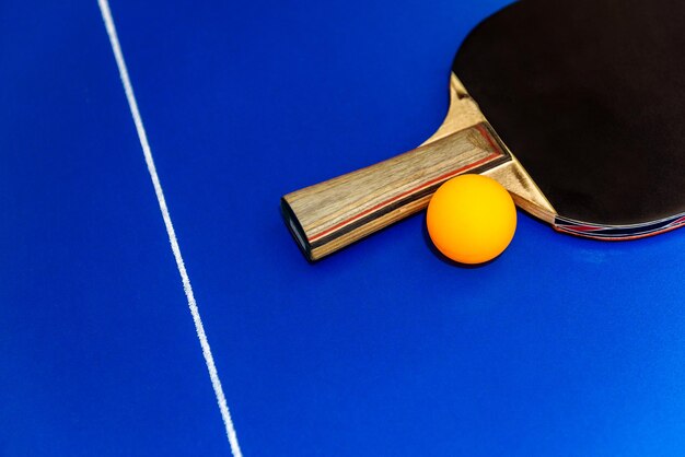 Rakietki do ping-ponga i piłki na niebieskim stole z siatką