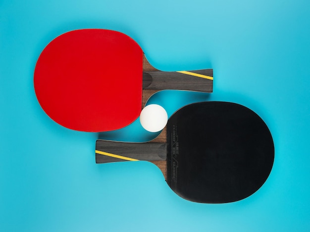 Rakiety tenisowe i piłka do ping-ponga na niebieskim tle