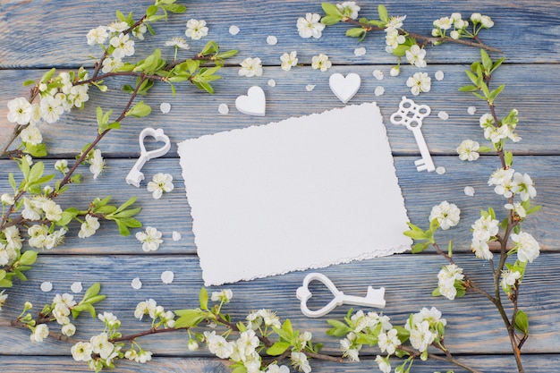 Zdjęcie rama kwitnących gałązek wiśni, kluczy, serc i pustych kartek papieru