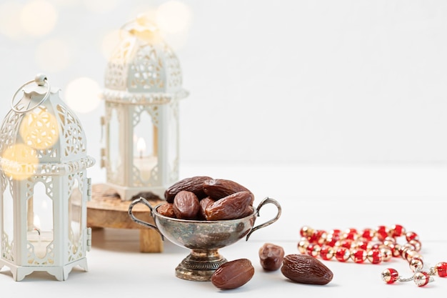 Ramadan Kareem i iftar muzułmańskie jedzenie, koncepcja wakacje. Misa z suszonymi daktylami, różańcem i latynokami ze świecami. Pomysł na uroczystość