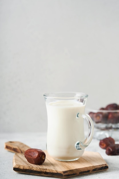 Ramadan Kareem jedzenie i napoje Talerz daktyli szklanka mleka i gałązka palmy daktylowej na jasnoszarym tle Sprawiedliwy styl życia muzułmanów Miejsce na tekst Selektywna ostrość