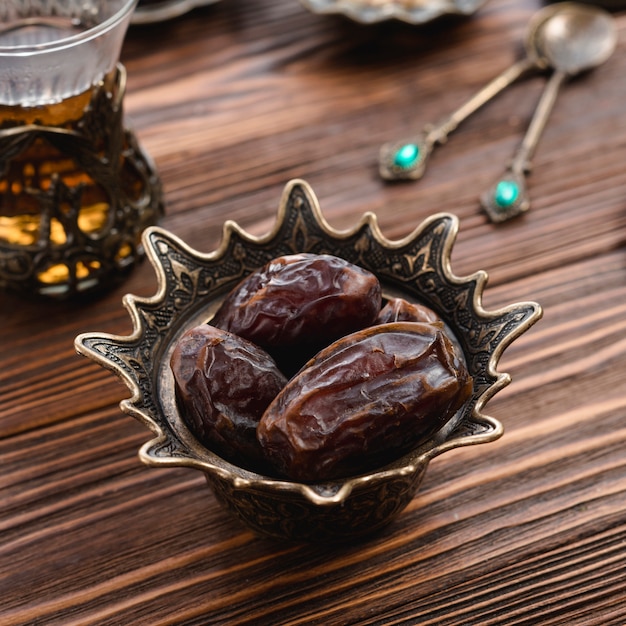 Ramadan wysuszona surowa organicznie daty owoc w kruszcowym pucharze na drewnianym textured tle