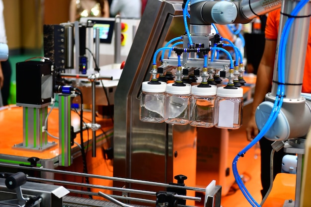 Ramię robota ułożyło szklaną butelkę na wodę na automatycznym sprzęcie maszyn przemysłowych na linii produkcyjnej