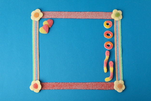 Ramka na zdjęcia wykonana z gumowatych cukierków na niebieskim tle, miejsca na tekst.