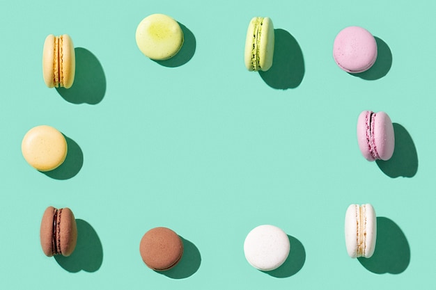 Ramka z Assorted Macaroons na jasnoniebiesko-zielonym kolorze, kolorowe francuskie ciasteczka macarons