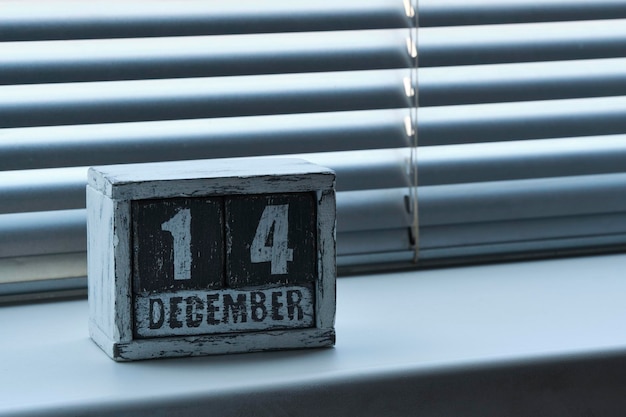 Zdjęcie ranek 14 grudnia na drewnianym kalendarzu stojącym na oknie z żaluzjami