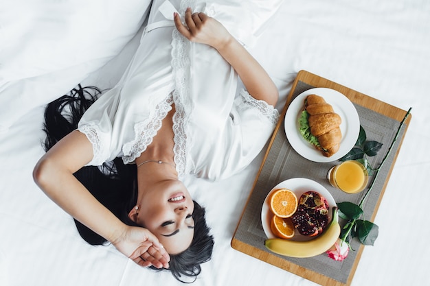 Zdjęcie rano pięknej dziewczyny w łóżku z jedzeniem
