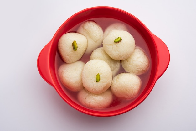 Rasgulla lub rosogulla - indyjskie słodycze z khoya, miękkie i gąbczaste, w glinianej misce na żółtej serwetce i brązowym tle