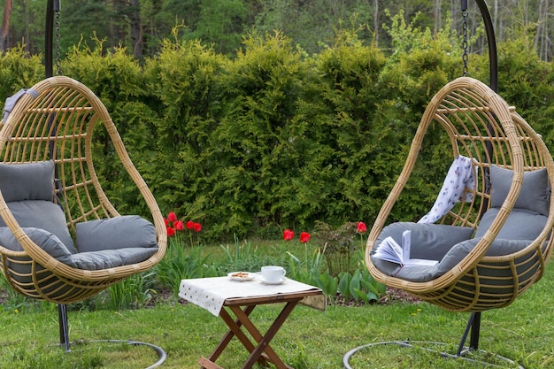 Rattanowa huśtawka ogrodowa z poduszką w ogrodzie na podwórku Koncepcja wakacji letnich
