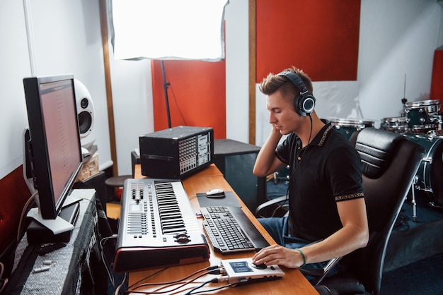 Realizator dźwięku w słuchawkach pracuje i miksuje muzykę w studiu.
