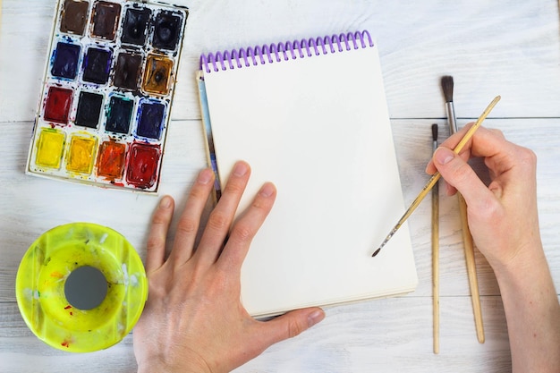 Zdjęcie ręce artysty paleta farb pędzle różne kolory dziewczyna rysuje narzędzia artysty do prawdziwej sztuki i inspiracji widok z góry