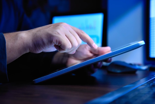 Ręce biznesmena używającego cyfrowego tabletu w wysokim biurze