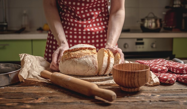 Ręce cięte nożem domowej roboty naturalny świeży chleb ze złotą skórką na drewnianym tle Pieczenie produktów piekarniczych