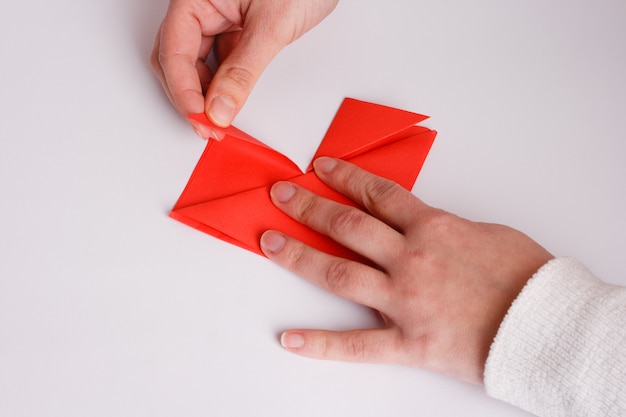 Ręce co serce origami z bliska na białym tle