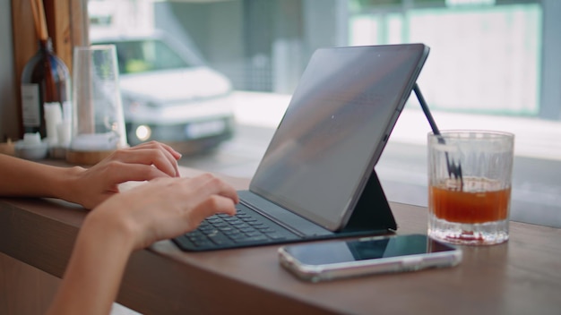 Ręce copywritera piszące na laptopie w kawiarni blisko nieznanego studenta studiującego