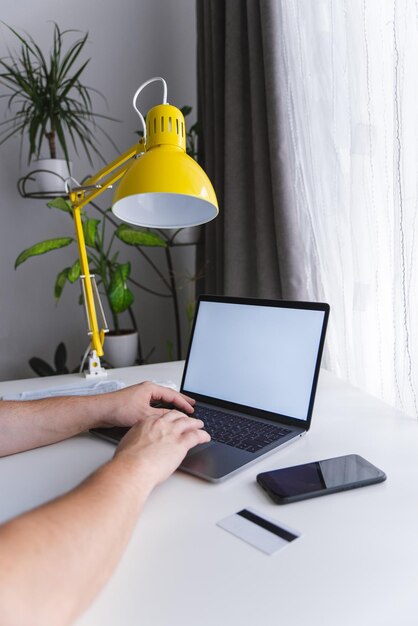 Ręce człowieka piszące na klawiaturze laptopa z białym ekranem laptopa wygląda jak macbook