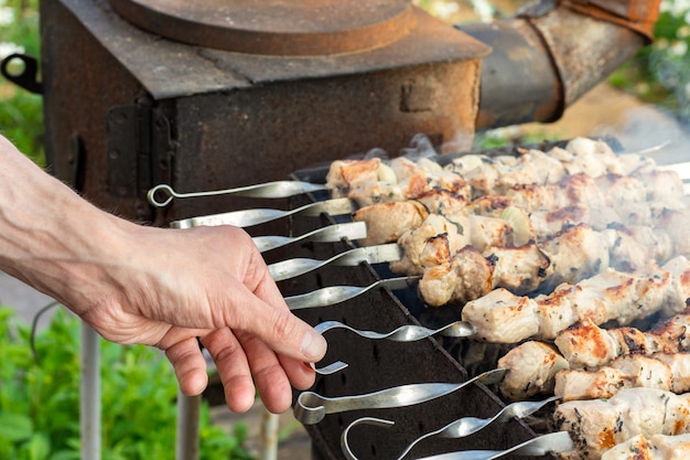 Ręce Człowieka Przygotowuje Mięso Z Grilla Na Szpikulec Przez Grill Na Ogniu Na Zewnątrz