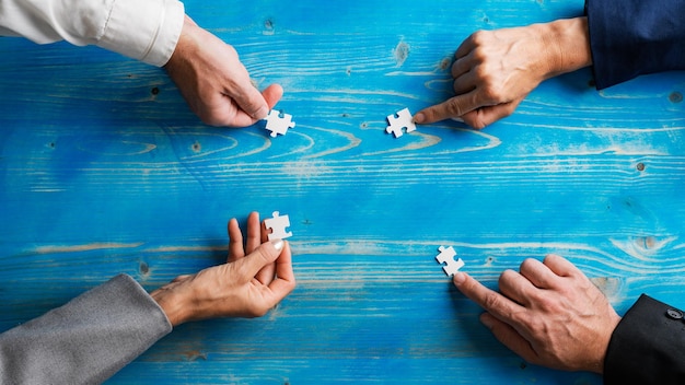 Zdjęcie ręce czterech ludzi biznesu, mężczyzn i kobiet, układających puzzle w kole
