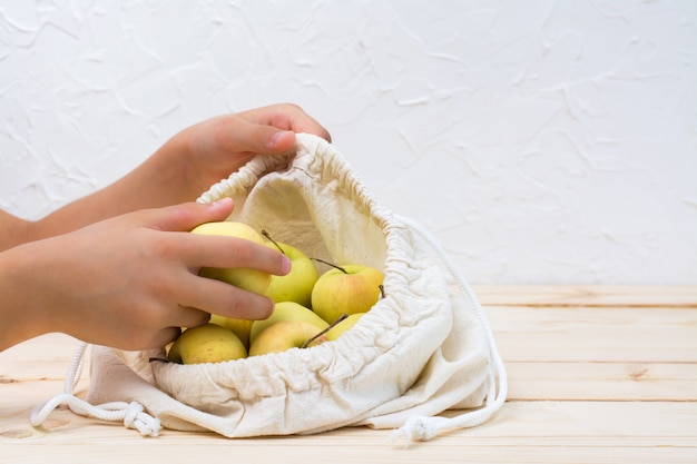 Ręce Dzieci Dodają Jabłka Do Płóciennej Torby Na Naturalnym Drewnianym Tle