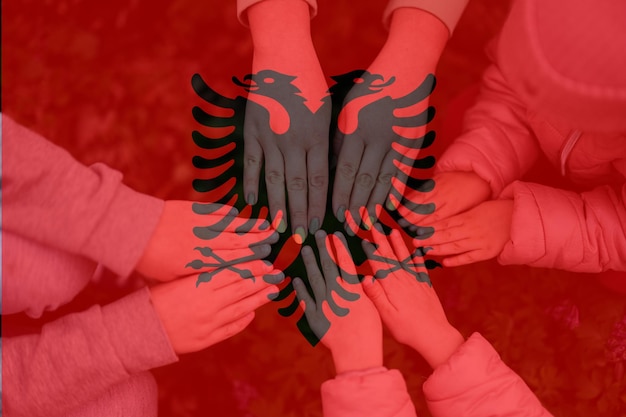 Ręce dzieci na tle flagi Albanii Albański patriotyzm i koncepcja jedności