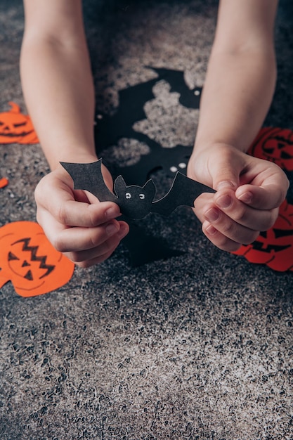 Ręce dzieci przygotowują dekoracje z papieru na Halloween Przygotowanie do święta