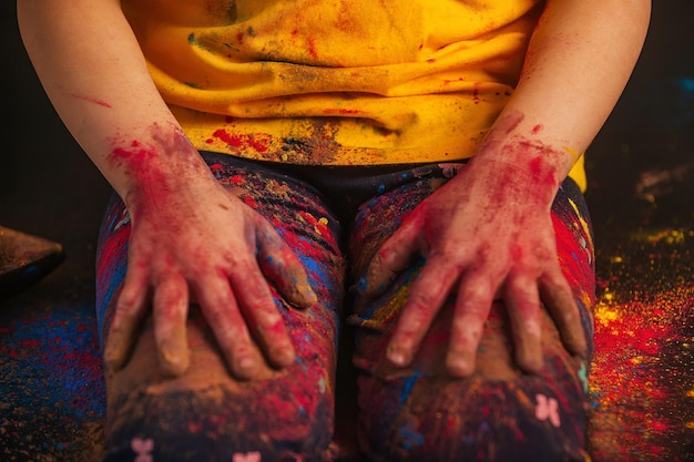 Zdjęcie ręce dzieci z bliska w kolorowych, żywych kolorach holi leżą na kolanach.