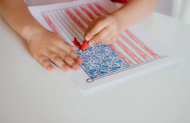 Zdjęcie ręce dziecka malują amerykańską flagę na białym stole rysunek dla dzieci flagi ameryki dzień niepodległości 4 lipca