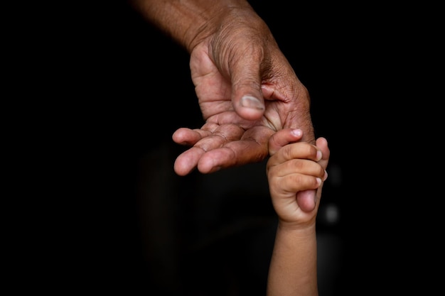 Ręce dziecka mocno trzymające Palec starości seniora Man39s Wsparcie pokolenia rodziny i koncepcja osób Ciemne tło