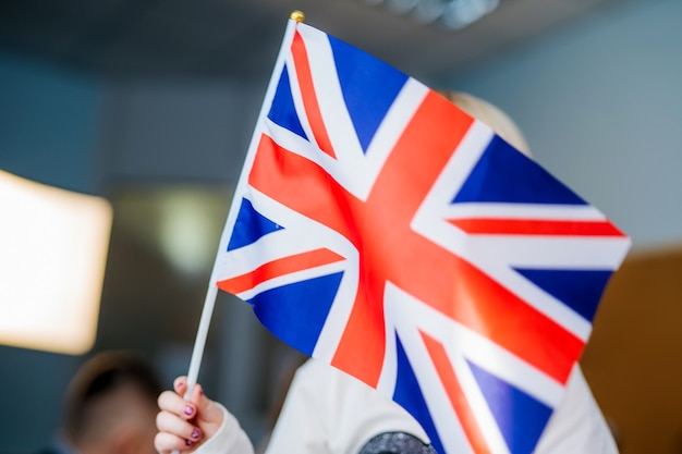 Ręce dziecka trzymają flagę Anglii Wielkiej Brytanii. Nauka języków obcych. Lekcja angielskiego. Zbliżenie.