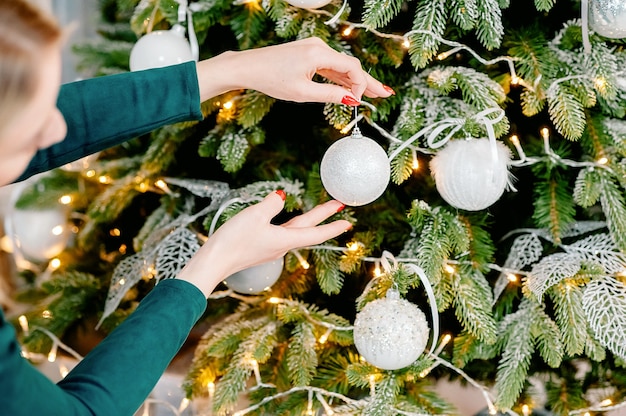 Ręce dziewczynki ozdabiają choinkę w Boże Narodzenie i sylwestra
