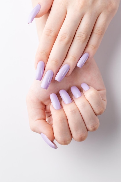 Ręce dziewczyny z miękkim fioletowym manicure'em na białym tle