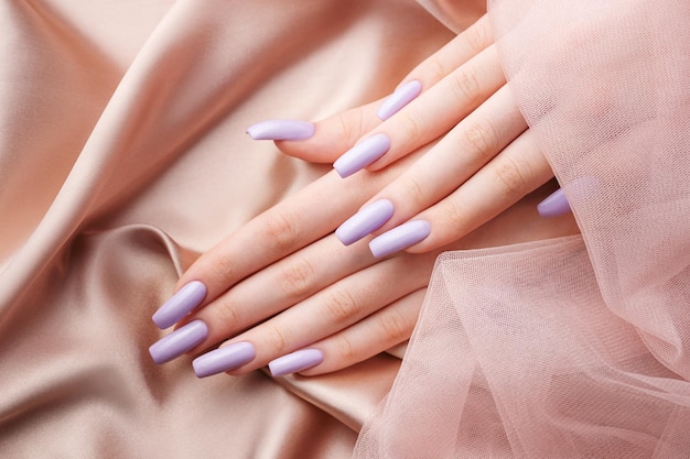 Ręce dziewczyny z miękkim fioletowym manicure