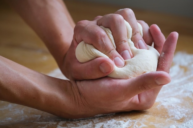 Ręce gniotą w dłoniach grudkę ciasta podczas gotowania i pieczenia chleba