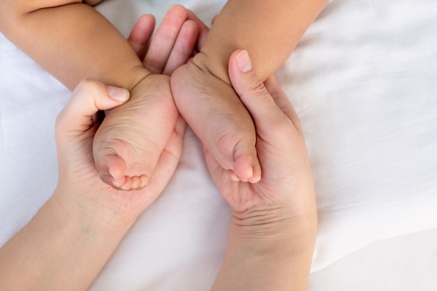 Ręce kaukaskiej mamy trzymającej małe nogi jej dziecka czarnego afrykańskiego dziecka.