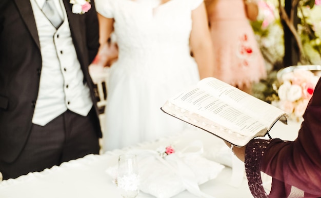 Zdjęcie ręce kaznodziei lub pastora trzymającego chrześcijańską biblię, wygłaszającego kazanie do koncepcji pary ślubnej, religii i boga w małżeństwie