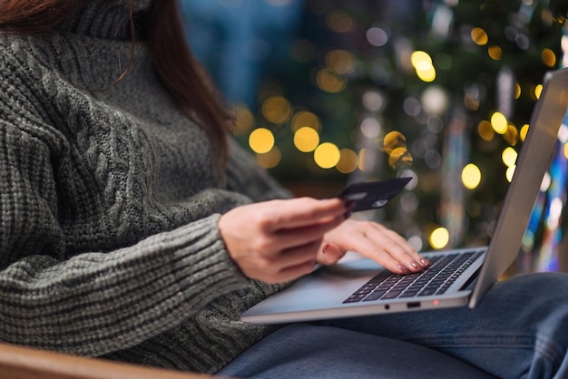 Zdjęcie ręce kobiet na laptopie z kartą kredytową i niewyraźnymi światłami bokeh