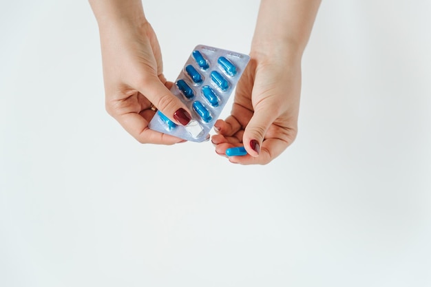 Ręce kobiet z niebieskimi kapsułkami w blistrze na białym tle Koncepcja farmaceutyczna i medycyna Kopiuj przestrzeń