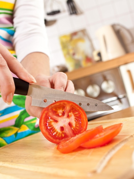 Ręce kobiety cięcie pomidora, ostry nóż.